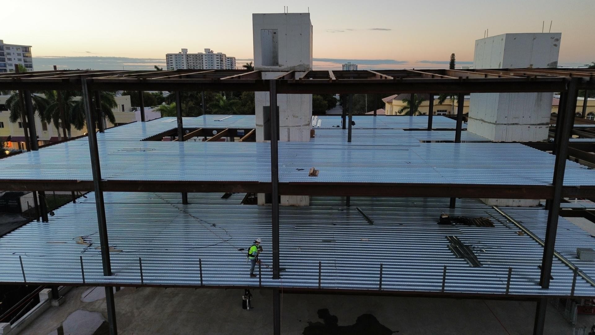 Worker walking across a steel roof deck on a building under construction.